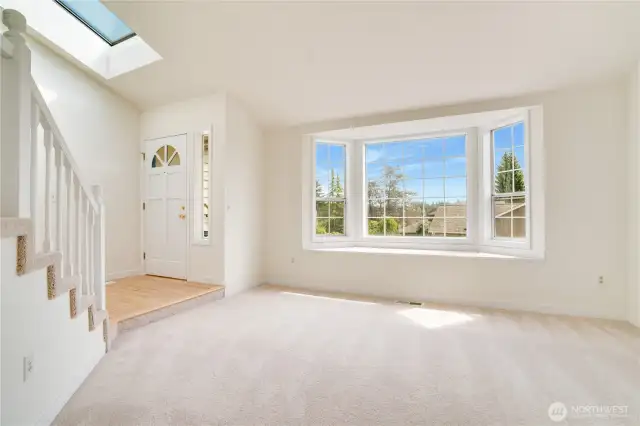 The formal living room features a grand bay window to bring in an abundance of natural light into the space. With the skylight above the front door, the sunshine really showcases the fresh paint and gleaming hardwood floors.