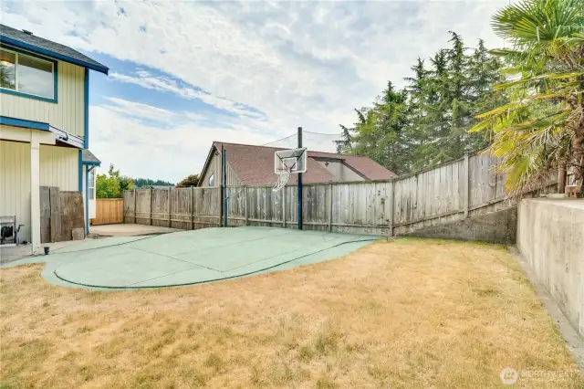 The backyard features a concrete basketball court with a backboard and hoop. Don't miss the dedicated firepit area too. This yard was made for entertaining!