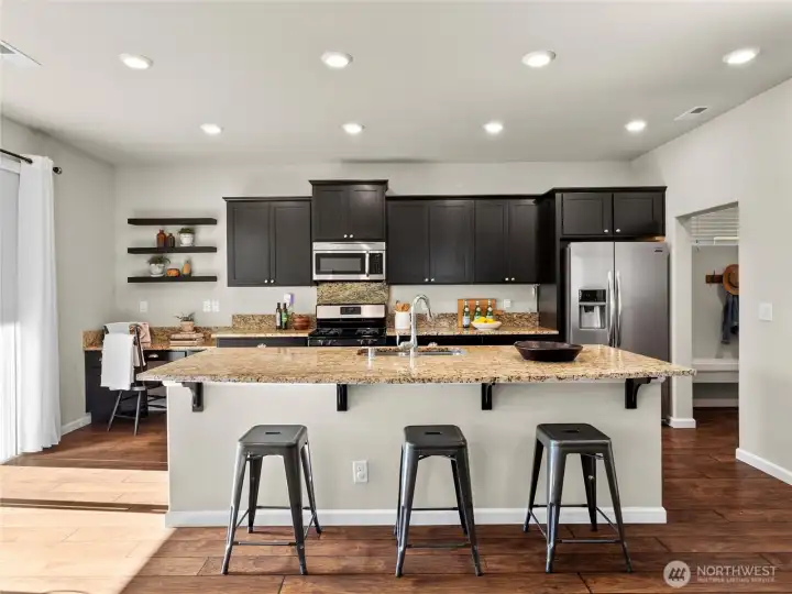 Modern kitchen with granite counters, stainless steel appliances, and bar seating.
