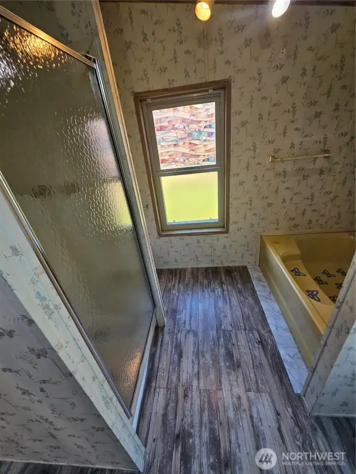 A separate enclosed shower is across from the large bathtub.