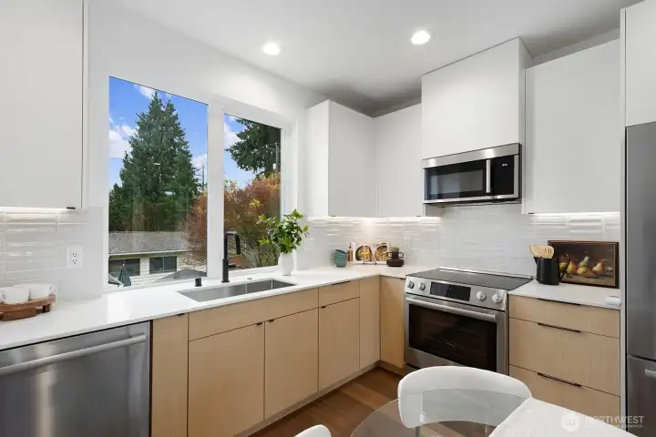 The large window frames the kitchen sink.