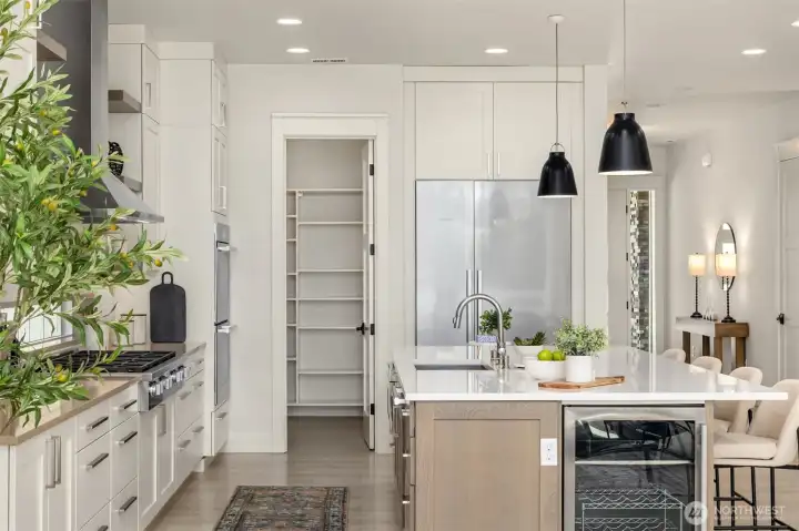 Well-appointed kitchen featuring SS Miele appliances, including an 8-burner gas cooktop, beverage refrigerator, built-in refrigerator, double ovens, and a convenient walk-in pantry with extensive shelving.