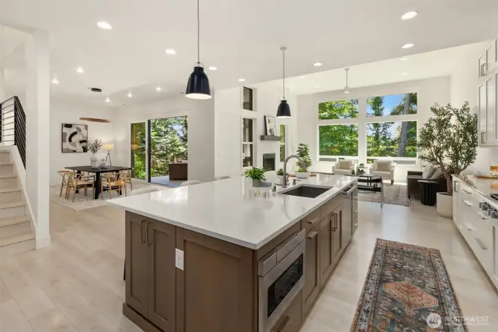 Kitchen flows seamlessly into the dining area, highlighted by soaring ceilings and abundant natural light.
