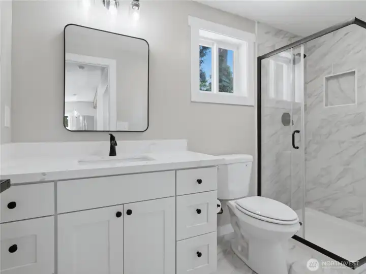 Main level bathroom has quartz counters and porcelain tile finishes