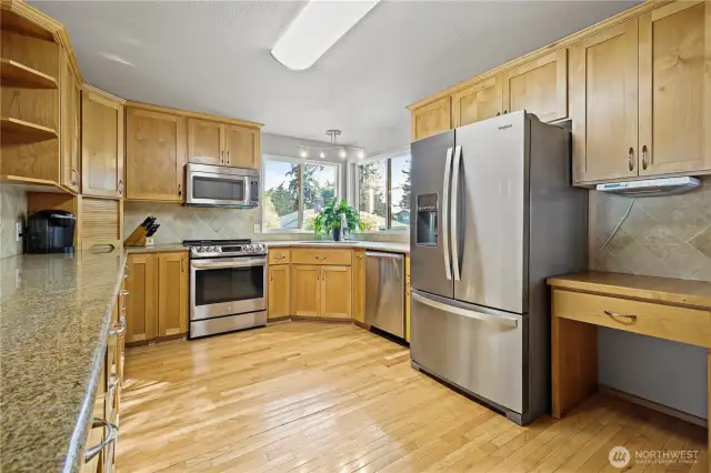 Spacious kitchen featuring abundant storage with solid maple cabinetry, stainless steel appliances included, and genuine oak hardwood flooring throughout.