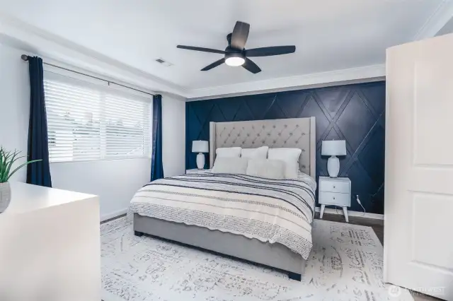 Primary with crown molding, accent wall, and ceiling fan for comfort