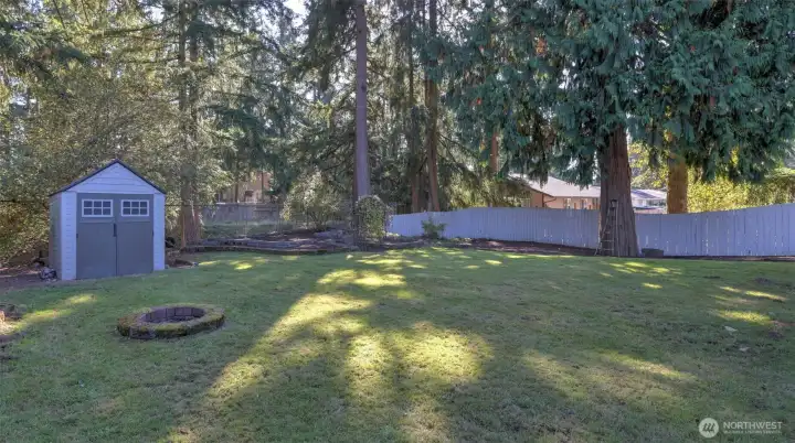 Shed and firepit in fenced yard.