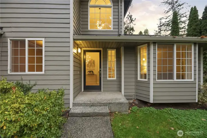 Stylish glass entry door and warm interior lighting create a truly welcoming first impression.