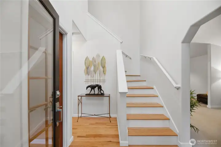Crisp refreshed entry with beautiful hardwood floors and a bright staircase, guiding you upstairs.