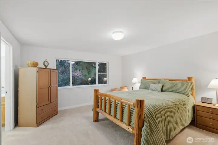 Spacious primary suite with a large windows overlooking the peaceful backyard and serene space to unwind.
