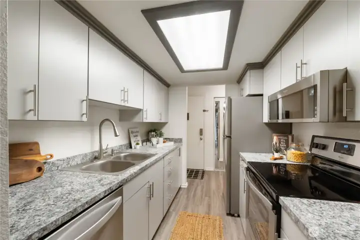 The galley kitchen offers plenty of cabinetry with handy slide-outs & decorative pulls. The stainless refrigerator is included