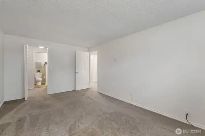 Another view of the primary suite looking out to the hallway and through the walk-in closet to the attached bath