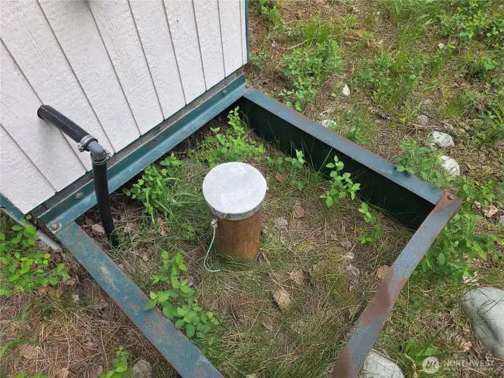 Water well for Lot 98 is wired for energy to pump. Pump house building next to well.