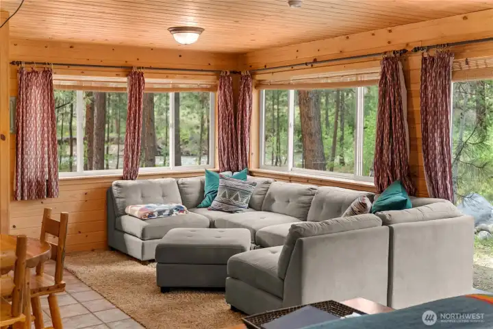 Cottage living area with natural light, nature out every window, and the sound of the river!