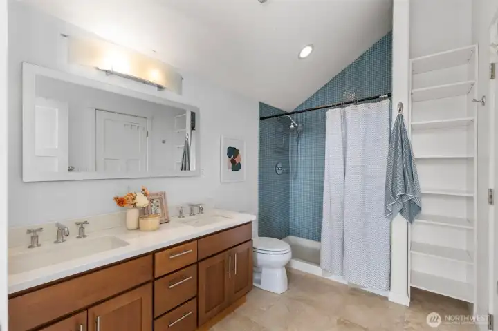 nice double sinks, shower and linens closet in primary bathroom
