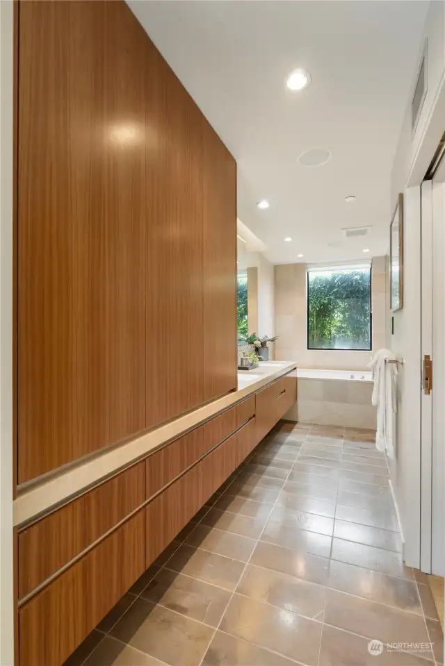 Primary Bathroom: This elegantly designed corridor leads to the primary bathroom, featuring beautiful built-in cabinetry with warm wood tones. The ample storage space and sophisticated design make it perfect for organizing personal items while adding a touch of luxury. Double sliding pocket doors provide seamless access to the spacious walk-in closet, enhancing the flow and functionality of the space. The inviting ambiance of this corridor sets the stage for the serene primary bathroom ahead, creating a harmonious transition between the areas.