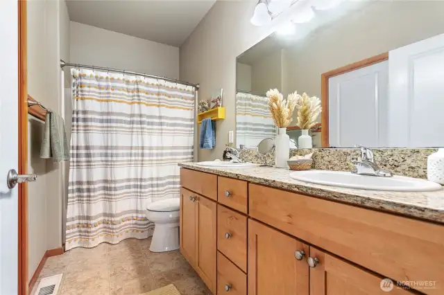 Main level primary suite with double sinks and granite counter