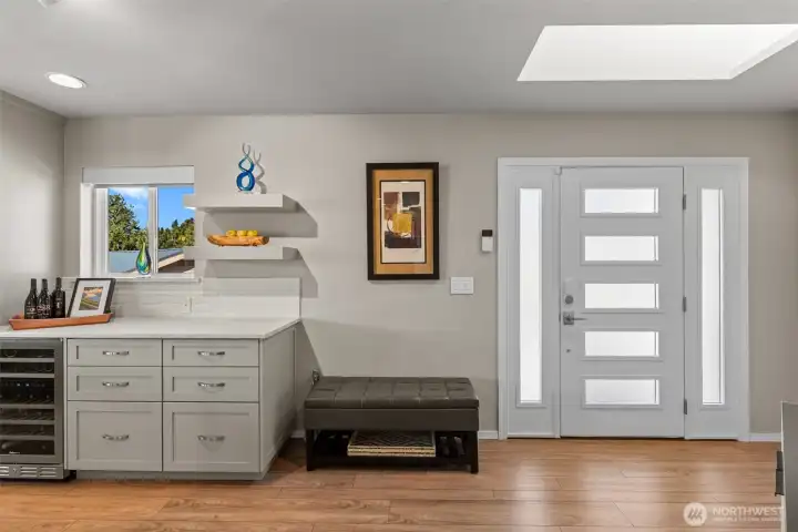 Bright and welcoming front entry featuring a frosted glass front door with matching sidelights and a skylight that fills the space with natural light.