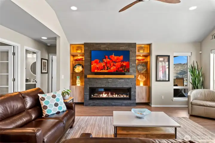 Smart home features include electric blinds and voice-controlled operation of illuminated built-ins, fireplace, TV, and even outdoor fountains for enhanced comfort and convenience. The French doors on the left lead to the office and the powder room is right next door, providing convenience and functionality on the main living level.