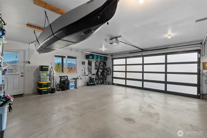 The attached 2-car garage is light and bright, featuring view-side windows and a translucent glass panel garage door that fills the space with natural light. A large mechanical room is accessed from the garage with abundant storage and has an extra refrigerator/freezer and separate freezer, which are negotiable.