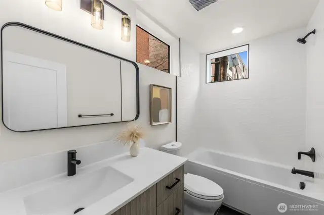 The large lower-level bedroom highlights an elongated custom vanity and full bathtub!