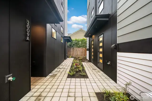 A landscaped paver walkway guides you from covered parking to the front steps, bordered by low-maintenance plantings. Photos are of model home 2009B.