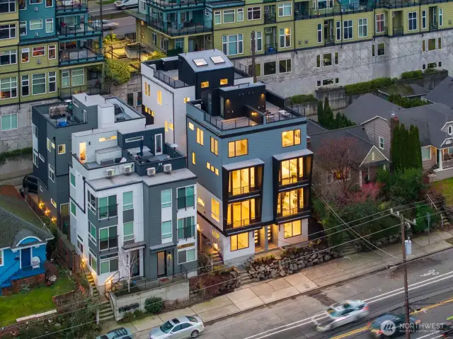 Mid-range aerial highlights the community’s pocket scale—only four homes, each with its own rooftop deck and street presence. Photos are of model home 2009B.