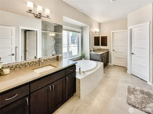 Primary bath offers dual vanities and soaking tub, tile flooring and quartz counters. His and Hers closets too!