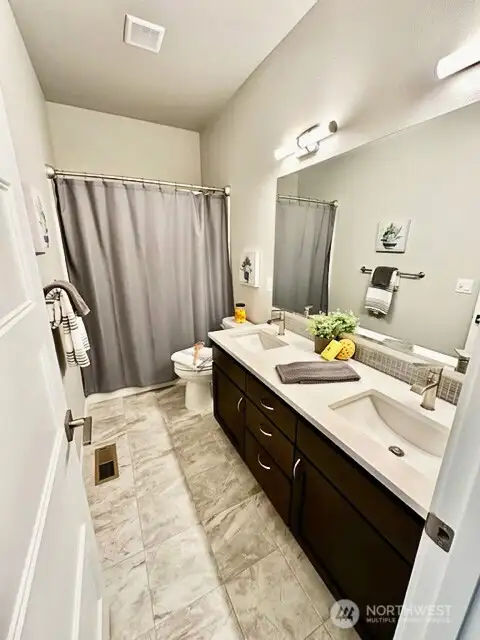 Stylish hall bath with dual vanity tile floors and quartz counters.