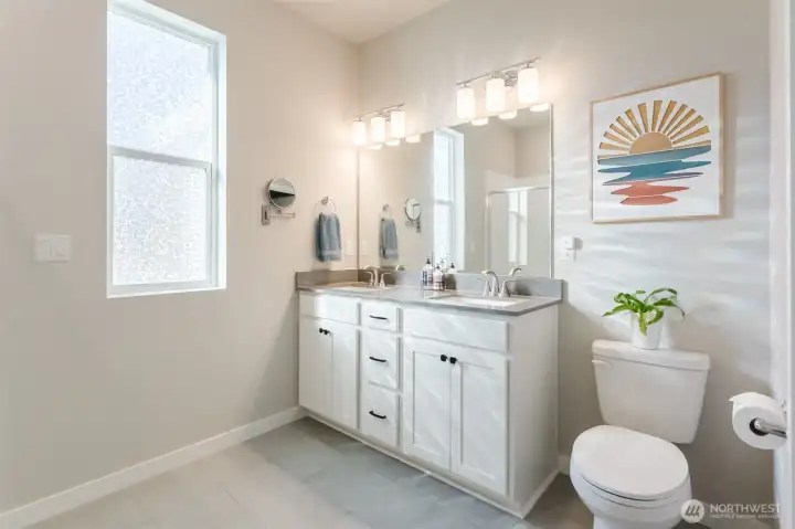 Well-appointed en-suite with dual sinks, quartz surfaces, and modern lighting.