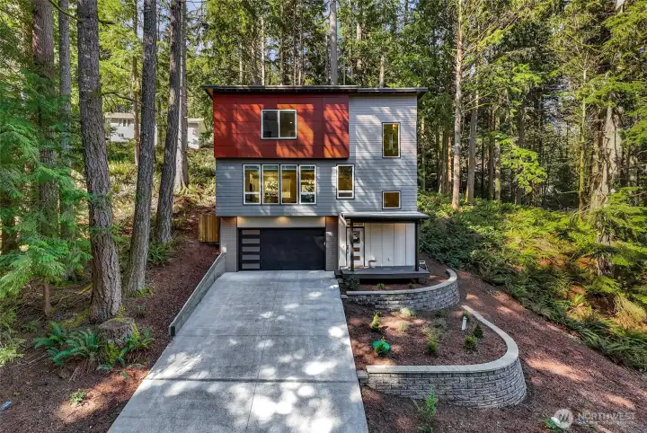 Welcome to 28 Hillside Pl. Contemporary exterior with clean lines, contrasting finishes, and a two-car garage set among mature evergreens.