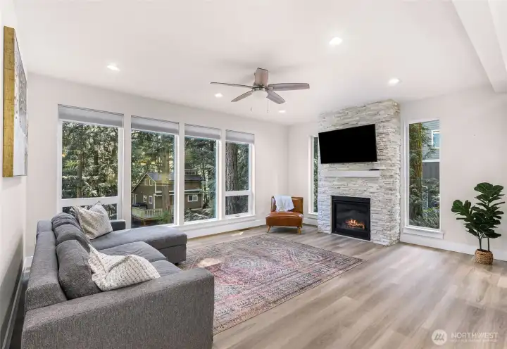 Living area with expansive windows bringing in natural light and wooded surroundings.