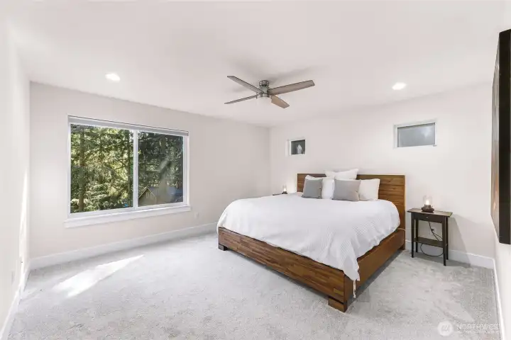 Spacious primary bedroom with large window and ceiling fan