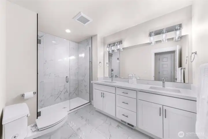 Primary bathroom with double vanity, modern finishes, and tiled walk-in shower