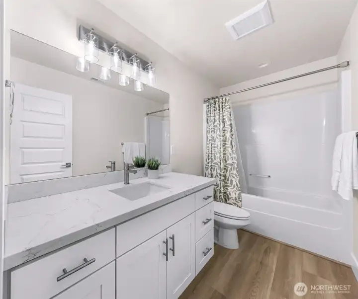 Full bathroom with quartz-style countertop, single vanity, and tub/shower combo