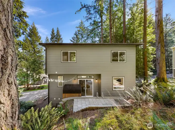 Rear exterior view with outdoor entertaining area and wooded backdrop