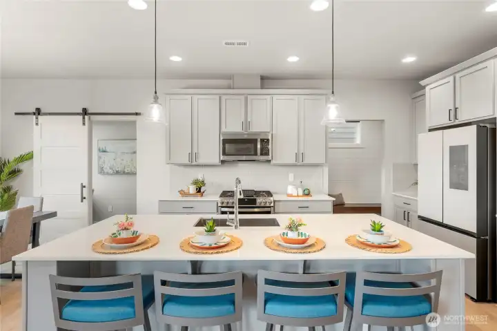 Large island contains plenty of space for snacks or homework, as well as a stainless steel sink and dishwasher.