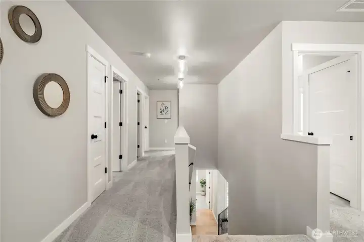 Upstairs hallway leads east from main bedroom past linen closet and full bath to three bedrooms. Door in right side of photo opens to the laundry room.