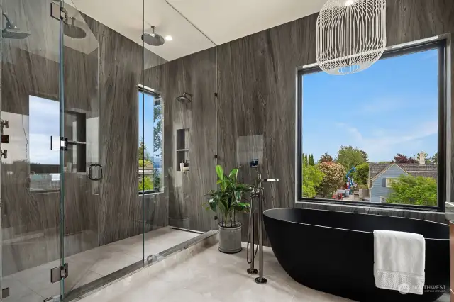 Sublime view primary suite with walk in closet, and luxurious 5 piece bath enhanced with walk in 2-head rain shower, soaking tub, floor to ceiling Platinum Grey Quartzite walls. Moreover, the 5-panel accordion doors offer optimal view + lead to private outdoor deck.