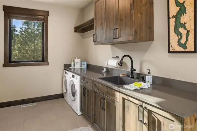 Huge utility room just off the 2 car garage, with sink and custom cabinets provides ample counterspace and bar for hanging clothes. Laundry chute delivers convenient connection to upstairs.