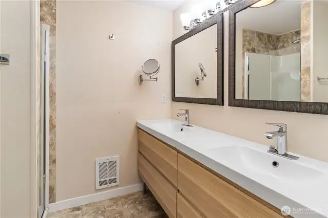 The updated primary bathroom has dual sinks, wall heat, a shower, new lighting and fixtures and it's both gorgeous and functional!