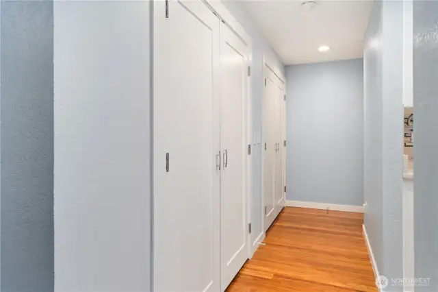 The hallway doors house the washer & dryer, the hot water heater, and lots of closet space. The kitchen is to the right.  Down the hall is where the private, primary bedroom is located.