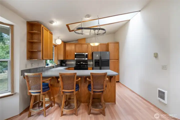 Kitchen offers bar seating, a pot rack and a skylight.