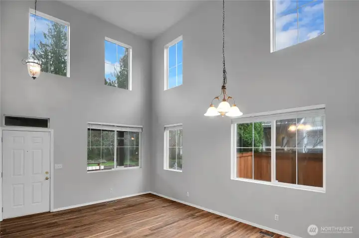 Formal living room with soaring ceilings, multiple windows, and LVP flooring