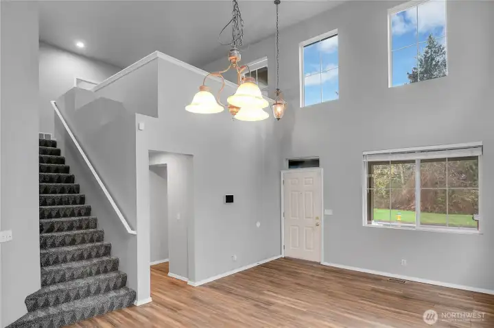Formal living room with soaring ceilings, multiple windows, and LVP flooring