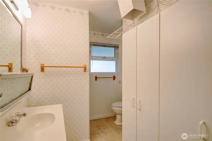 Lower level 3/4 bath with storrage cabinets and laundry shoot from the primary bedroom upstairs.
