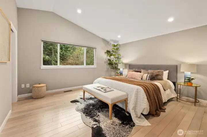 Primary bedroom with vaulted ceilings and hardwood floors.