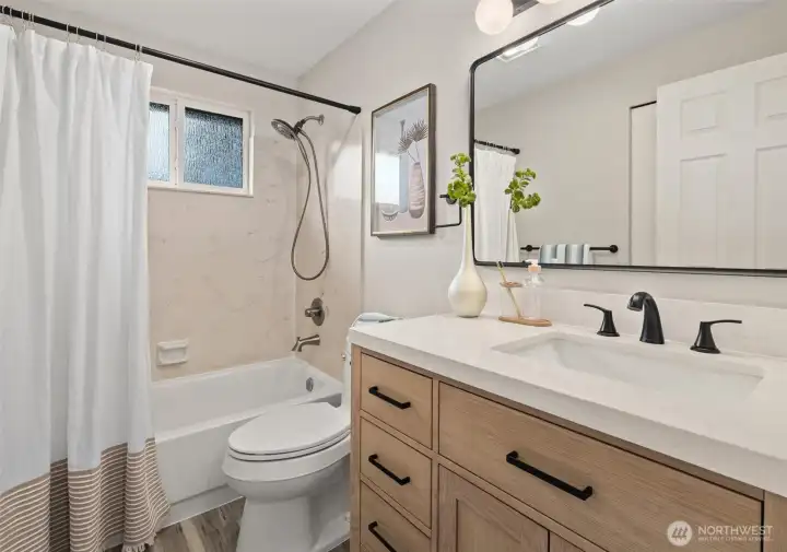 Full hall bath with modern vanity and quartz countertop on the upper level.