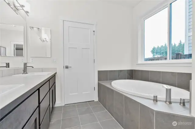 primary bath includes 2 sink vanity, tile flooring and soaking tub with tile decking. Photo for illustration only of similar home, not actual.