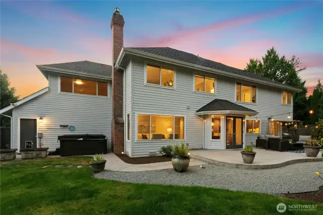 Back of home features hot tub, concrete stamped patio, extra large garden shed, and fully fenced flat backyard.